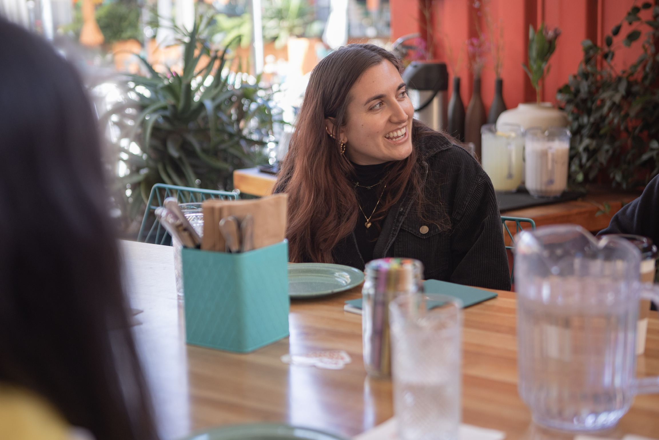 A young women talking at dinner table out with friends.